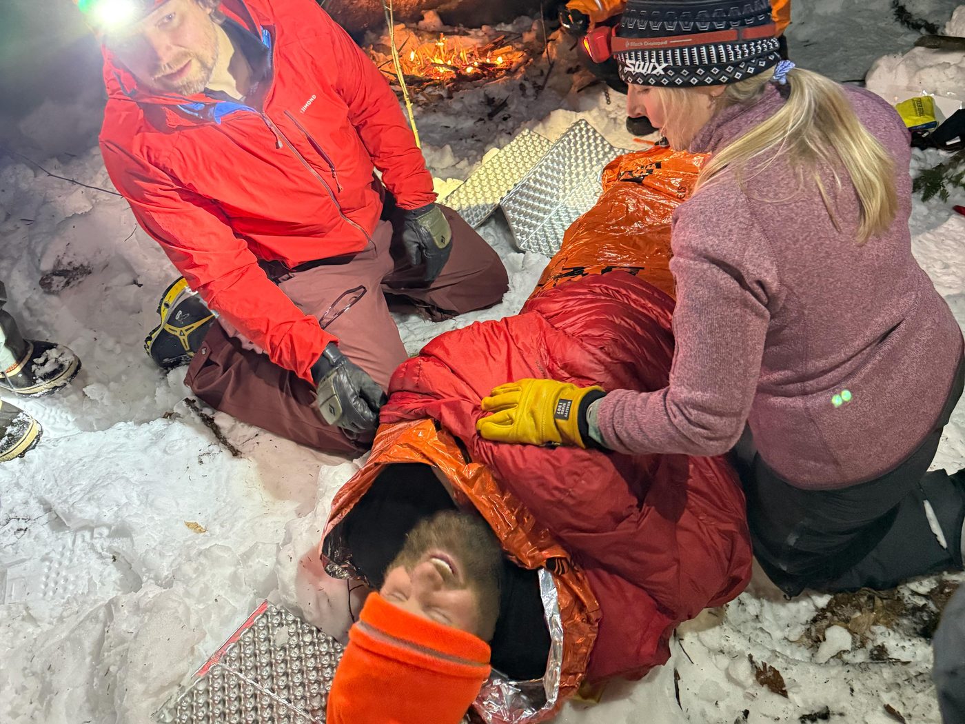 KSAR members wrap a volunteer patient in an orange thermal blanket and sleeping bag during a night training